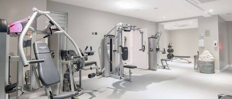 Et moderne fitnessrum med diverse træningsmaskiner, en bænk og et vægmonteret stativ.