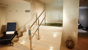 A spa area with a hydrotherapy pool, a massage chair, and a staircase leading to a higher level.