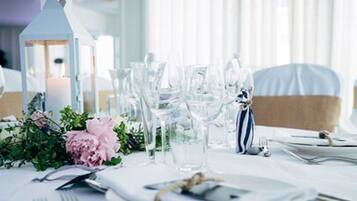 A table set for a formal event with clear glassware, a candle, and a floral centerpiece.