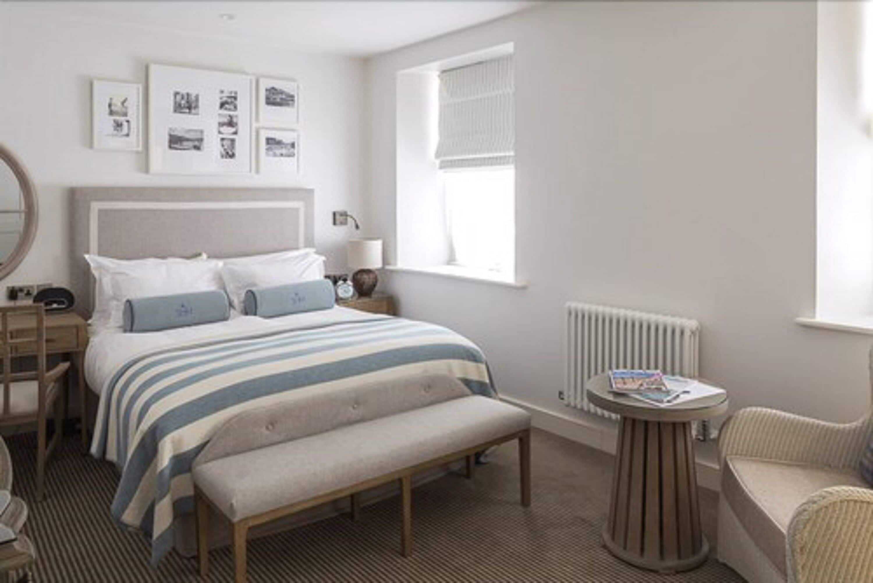 A bedroom with a bed, bedside table, lamp, and a window with blinds.