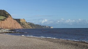 A pebble beach with a rocky cliff and calm sea. - Harbour Hotel Sidmouth (Sidmouth)