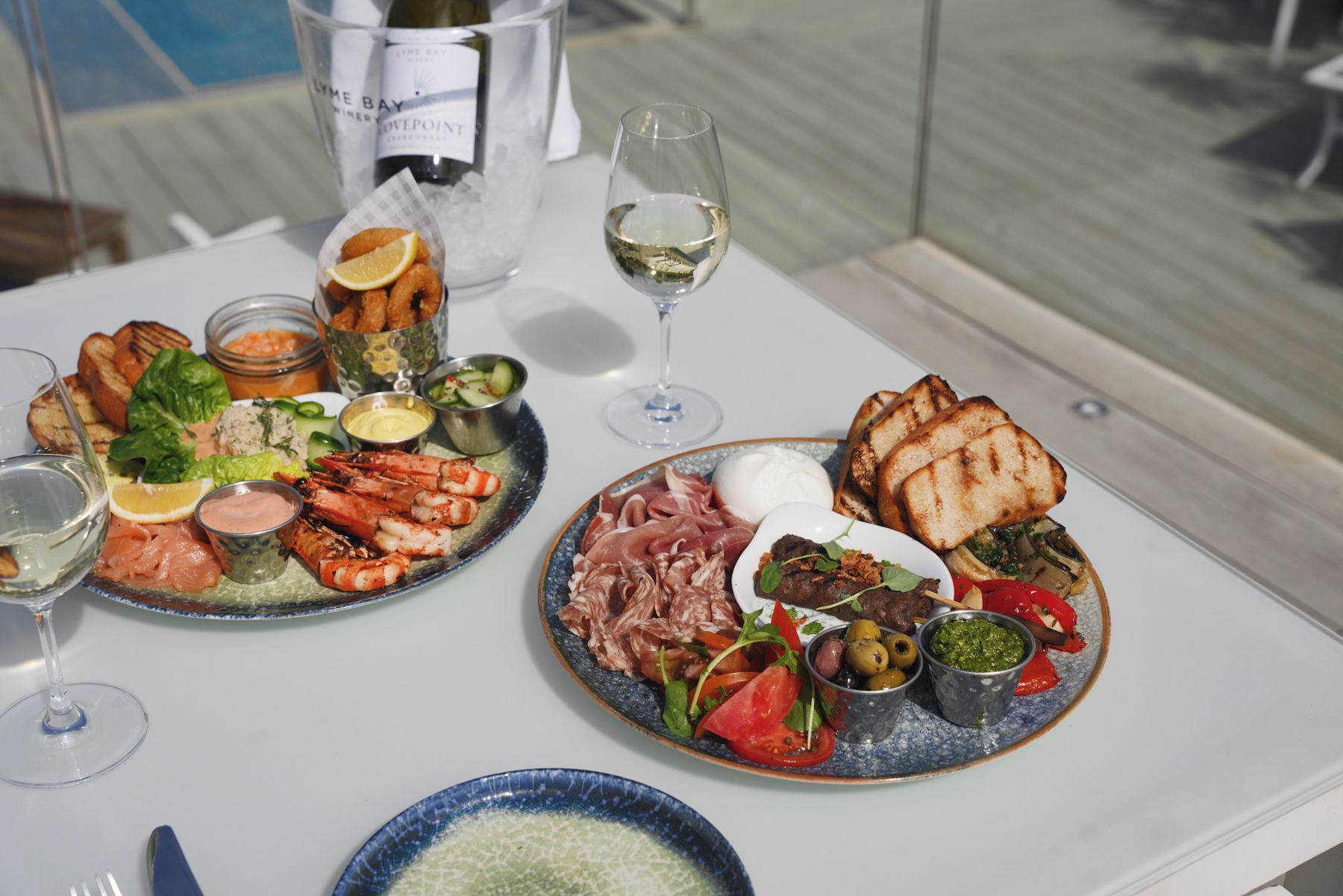 Une table garnie de divers aliments, notamment des fruits de mer, des viandes et des légumes, accompagnée de boissons et de condiments.