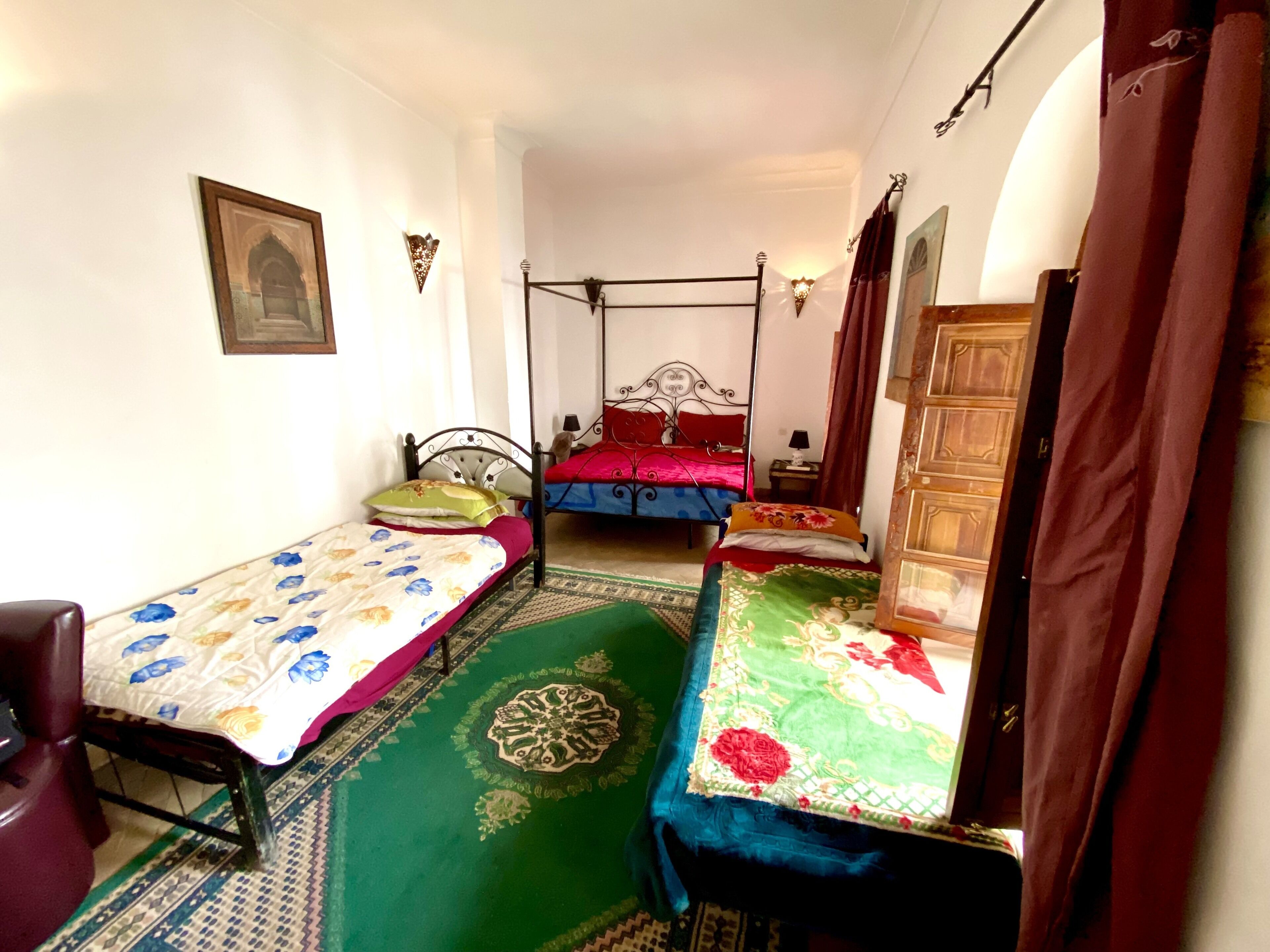 A room with two single beds, a chair, a wooden wardrobe, and a patterned carpet.