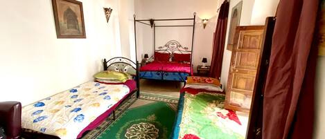 A room with two single beds, a chair, a wooden wardrobe, and a patterned carpet.