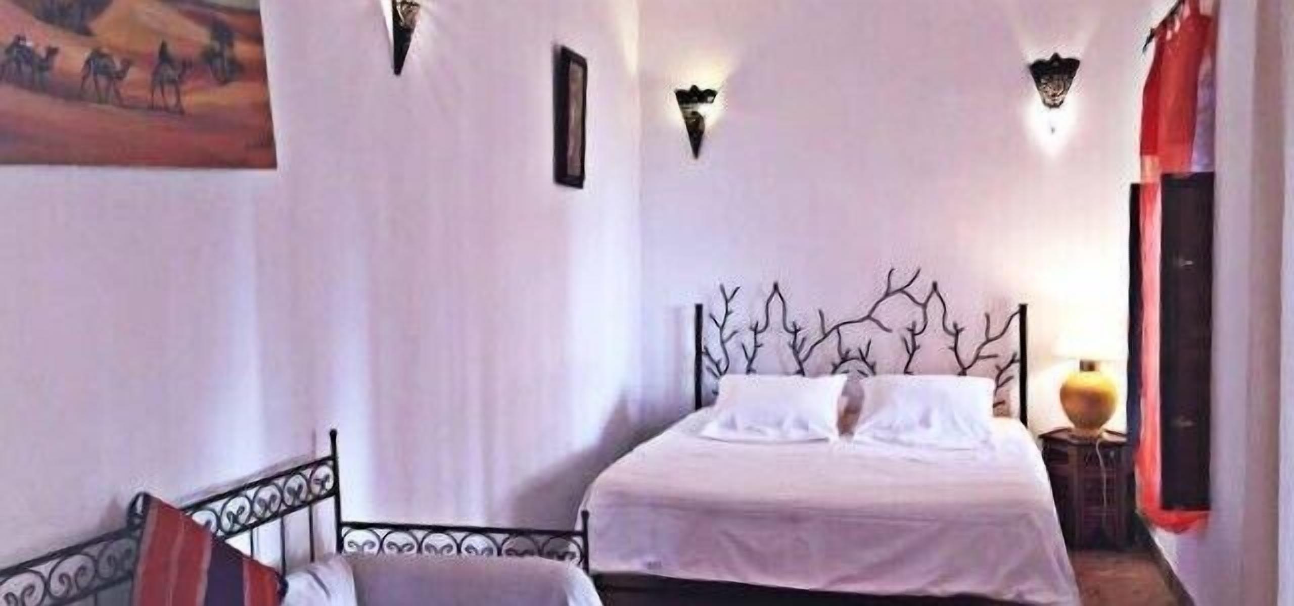 Une chambre à coucher avec un lit, une chaise et un tableau accroché au mur.