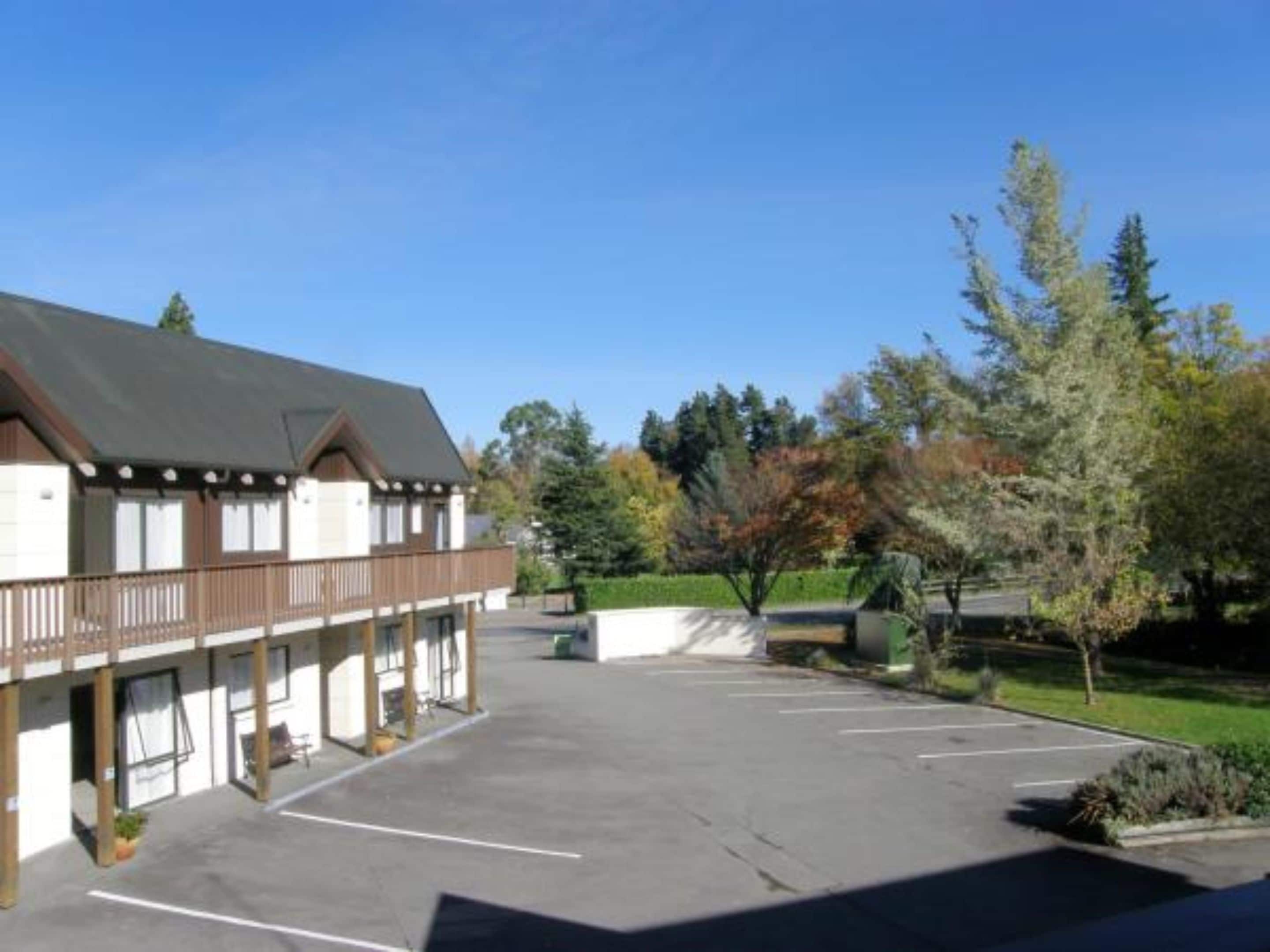Un bâtiment à deux étages doté d’un balcon, d’un parking et d’arbres aux feuilles d’automne.