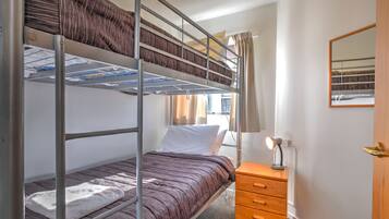 A bunk bed room with a wooden nightstand and a mirror.