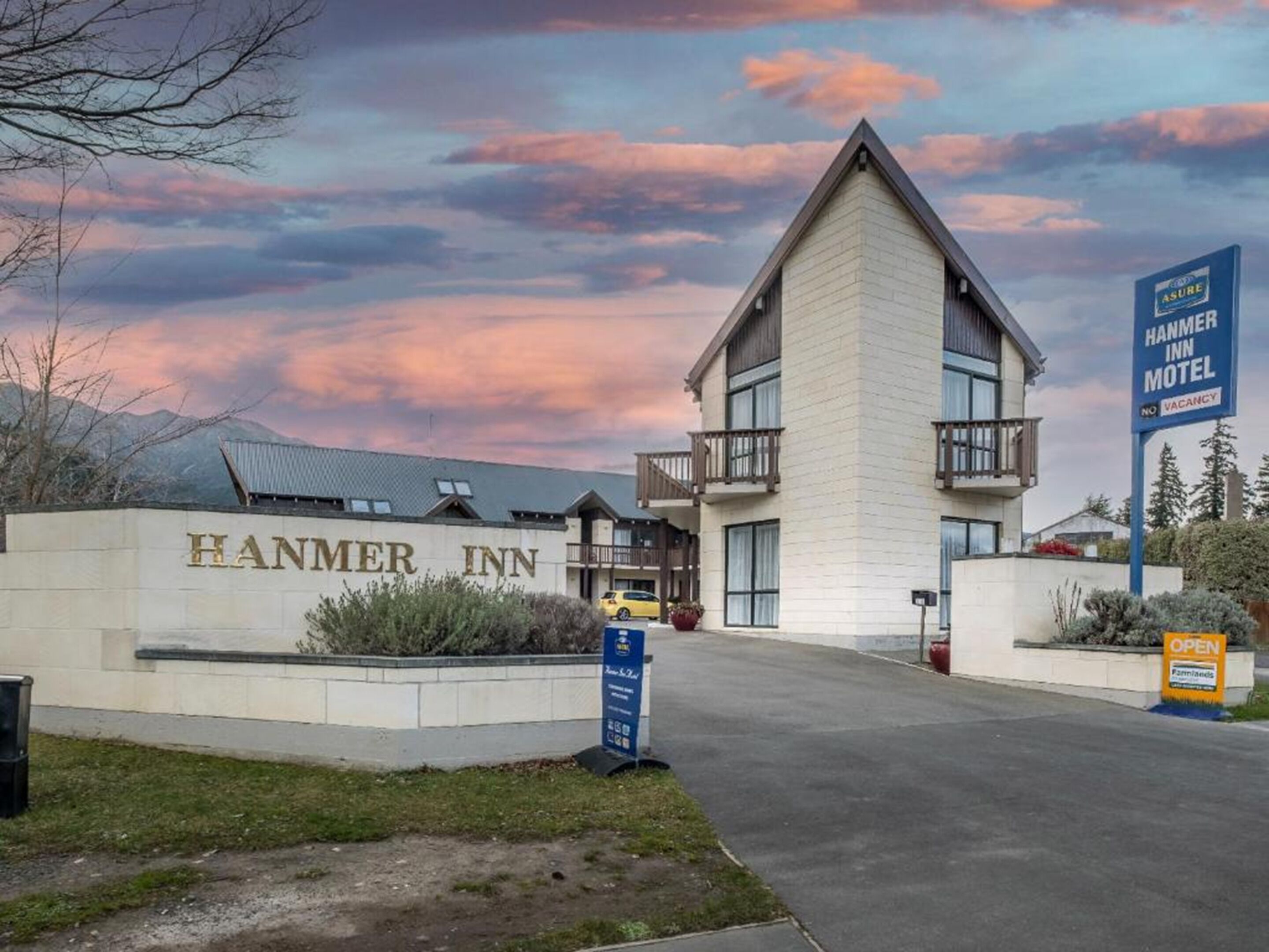 The exterior of the Hammer Inn Motel with a prominent sign, a parking area, and a clear view of the building's architecture.