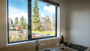 A kitchen with a large window, a sink, and a wine bottle. - ASURE Hanmer Inn Motel (Hanmer Springs)