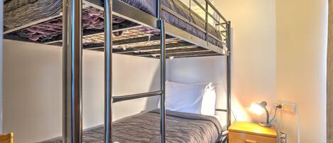 A bunk bed room with a wooden dresser and a lamp.