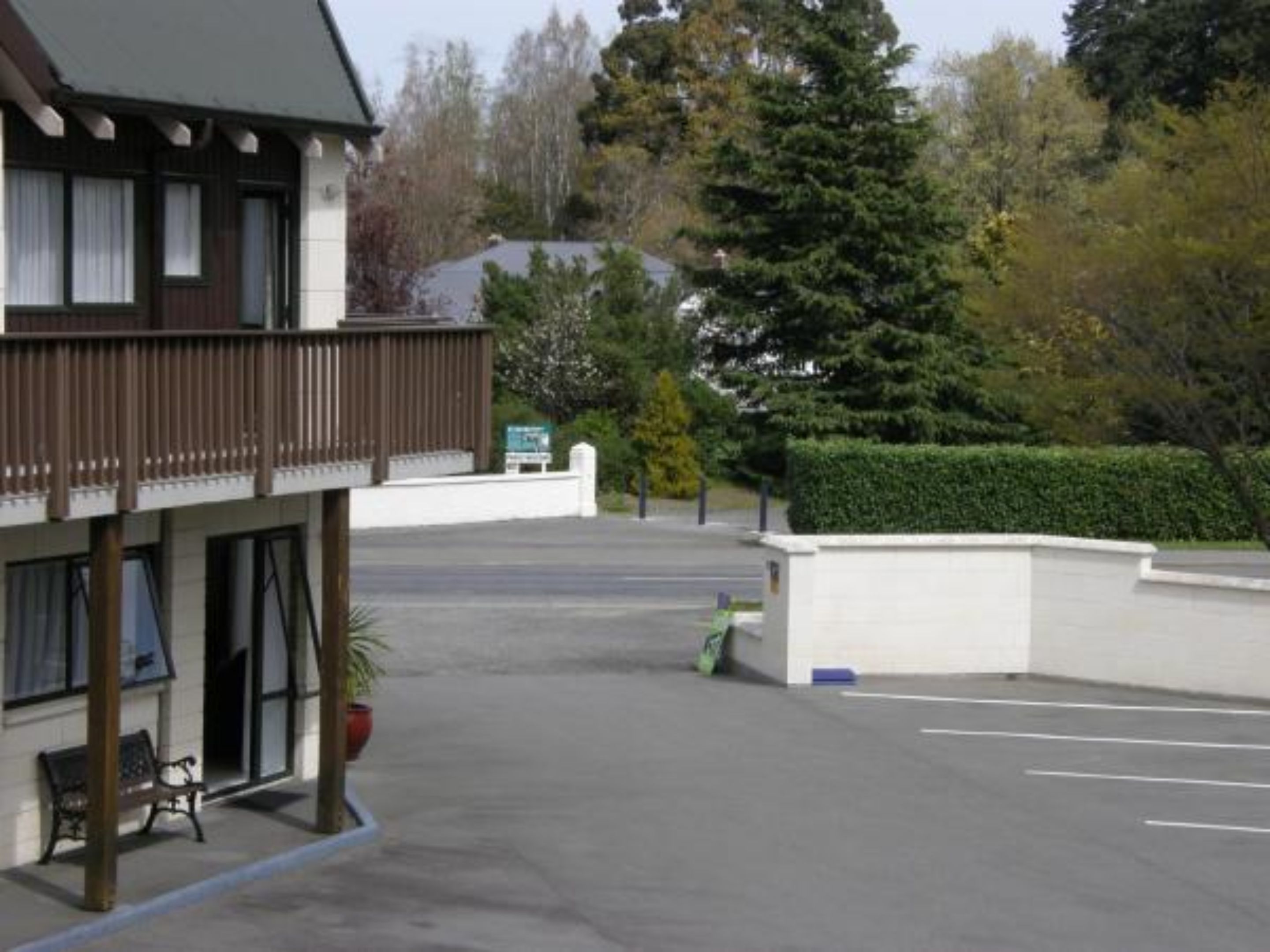 Een gebouw met balkon, parkeerplaats en een groen bord.