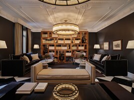 A luxurious room with a large bed, two sofas, a round coffee table, and a bookshelf filled with books.