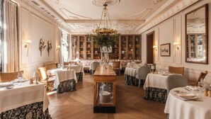 Un comedor formal con varias mesas, elegantes candelabros y decoración clásica.