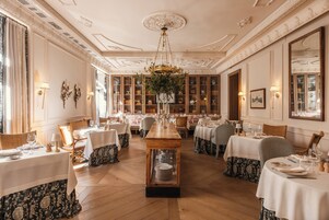 A formal dining room with multiple tables, elegant chandeliers, and classic decor.