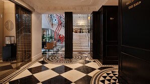 Un vestíbulo de hotel con piso a cuadros, una escalera y una mesa de recepción.