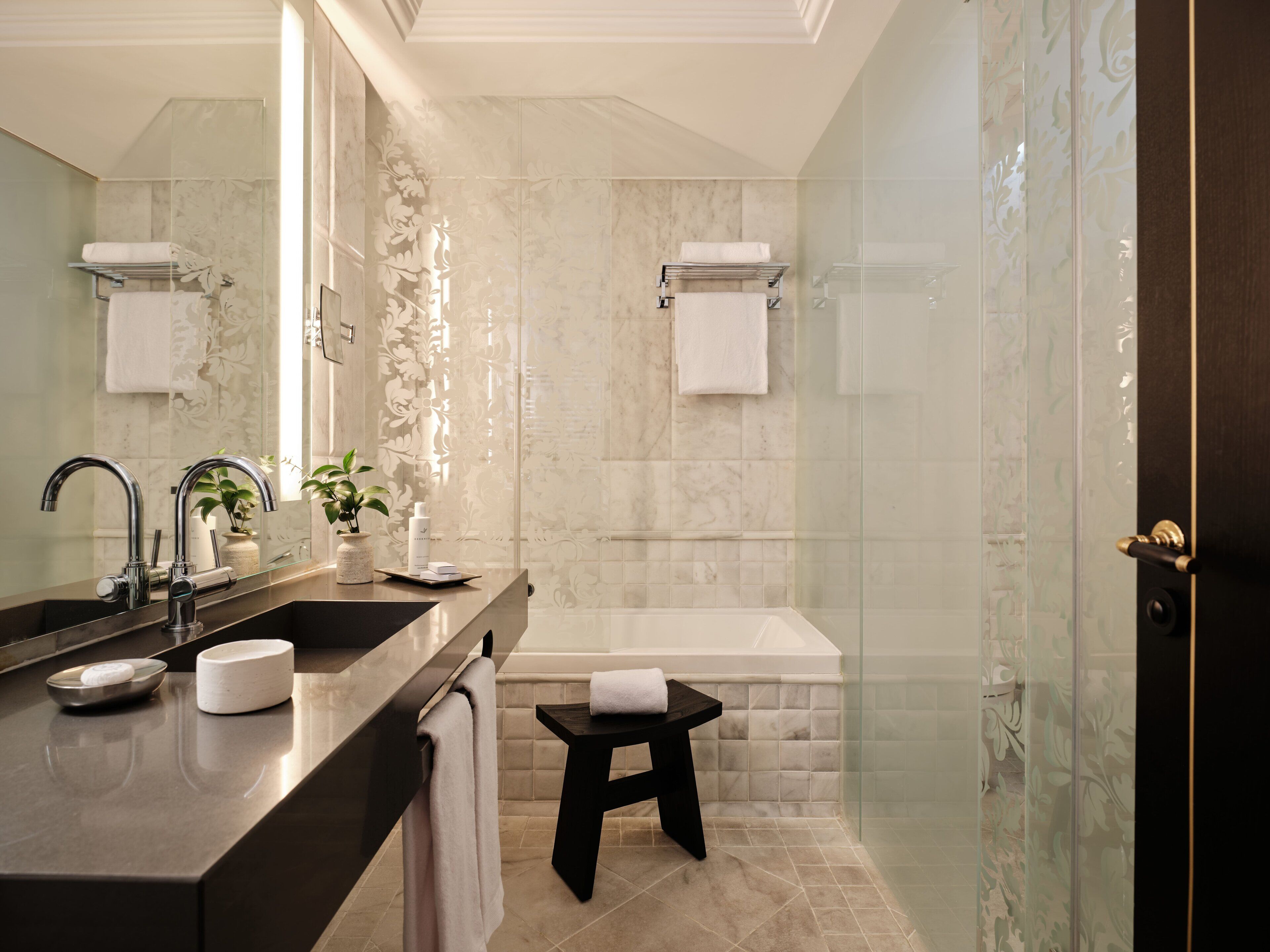 Un baño moderno con un tocador de doble lavabo, un espejo grande, cabina de ducha de cristal y bañera independiente.
