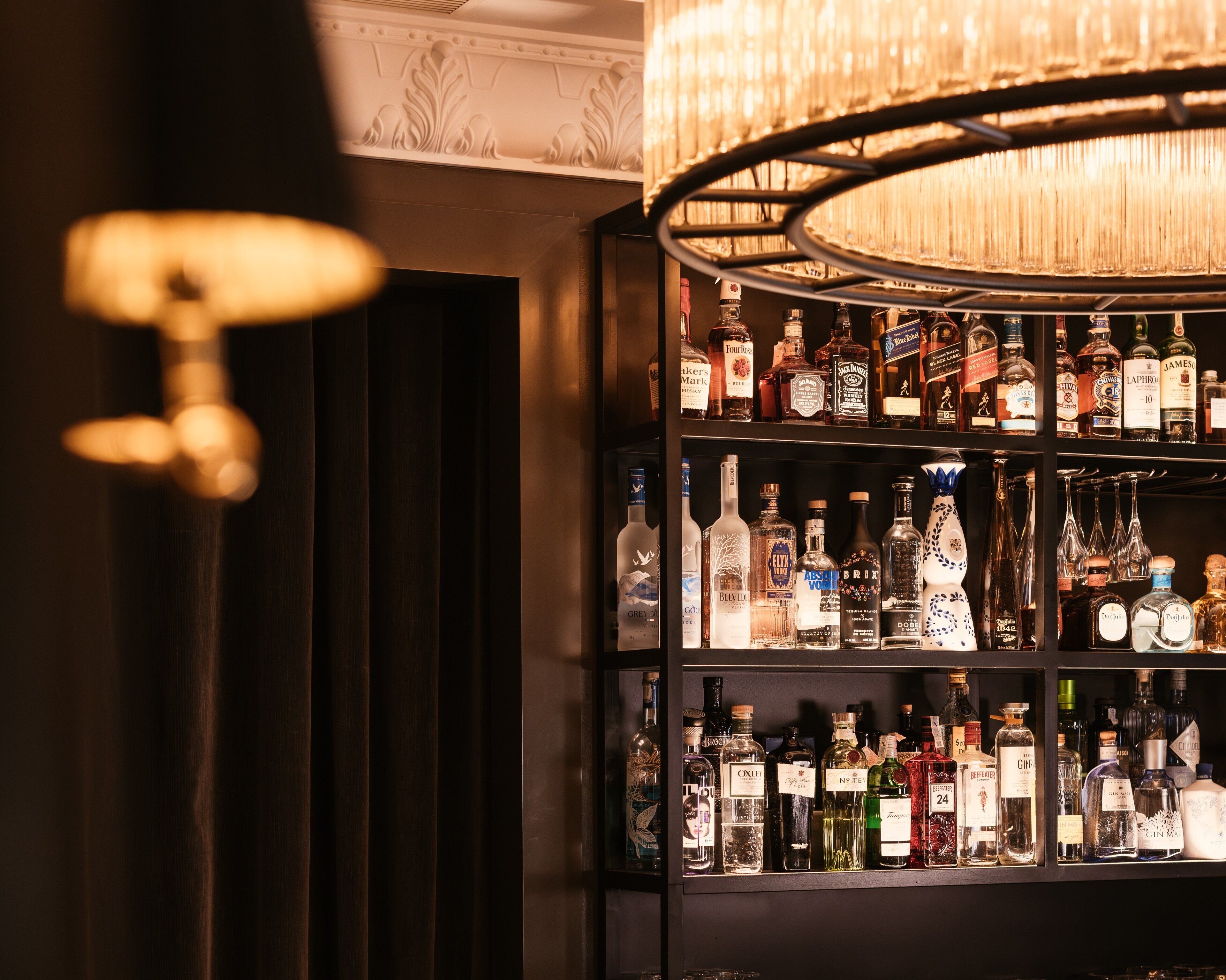 A bar area with shelves of liquor bottles and a decorative chandelier.