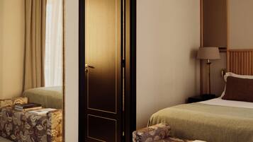 A hotel room with a bed, a sofa, a bedside table, a lamp, and a mirror.