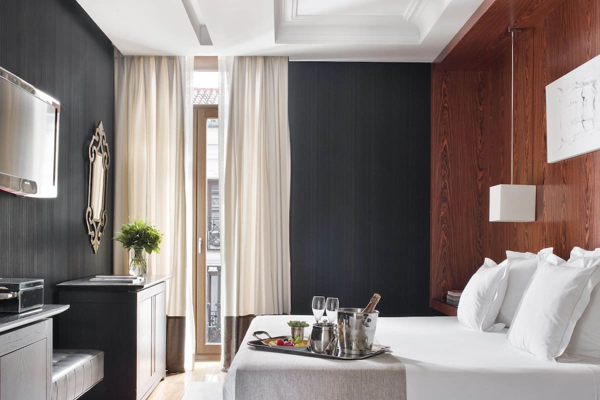 Une chambre d’hôtel moderne équipée d’un lit, d’une table de chevet, d’une télévision et offrant une vue sur l’extérieur.