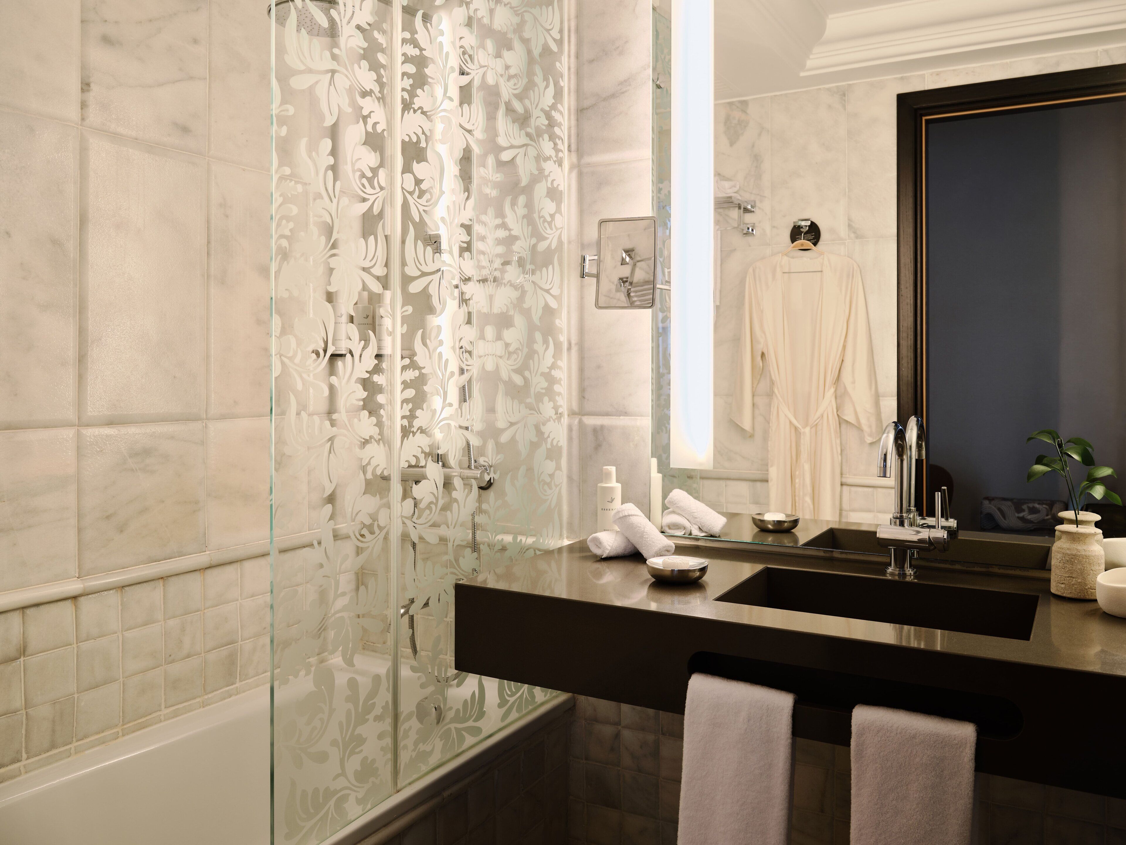 A modern bathroom with a glass shower enclosure, a black countertop sink, and a large mirror.