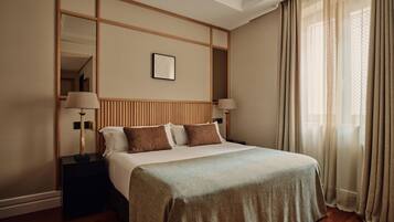 A hotel room with a large bed, a nightstand, a mirror, and a window with curtains.