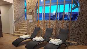 Un espace de détente comprenant trois fauteuils inclinables, un mur carrelé, une horloge et un escalier.