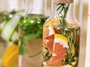 A bottle with a cork stopper, containing a liquid, lemon slices, and rosemary. - Mercure Marijampole (Marijampole)