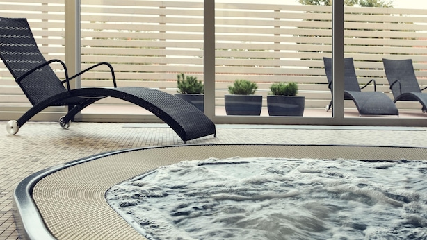 Un bain à remous de forme circulaire, entouré de chaises longues et de plantes en pot.