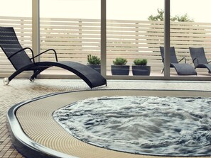 Un jacuzzi de diseño circular, rodeado de sillones de descanso y plantas en macetas.