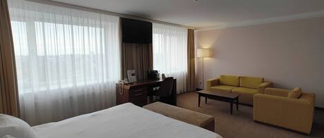 A hotel room with a bed, a desk, a sofa, and a lamp.