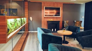 Un espace de détente moderne doté d’un grand aquarium, de sièges confortables, d’une cheminée et d’un grand écran de télévision.