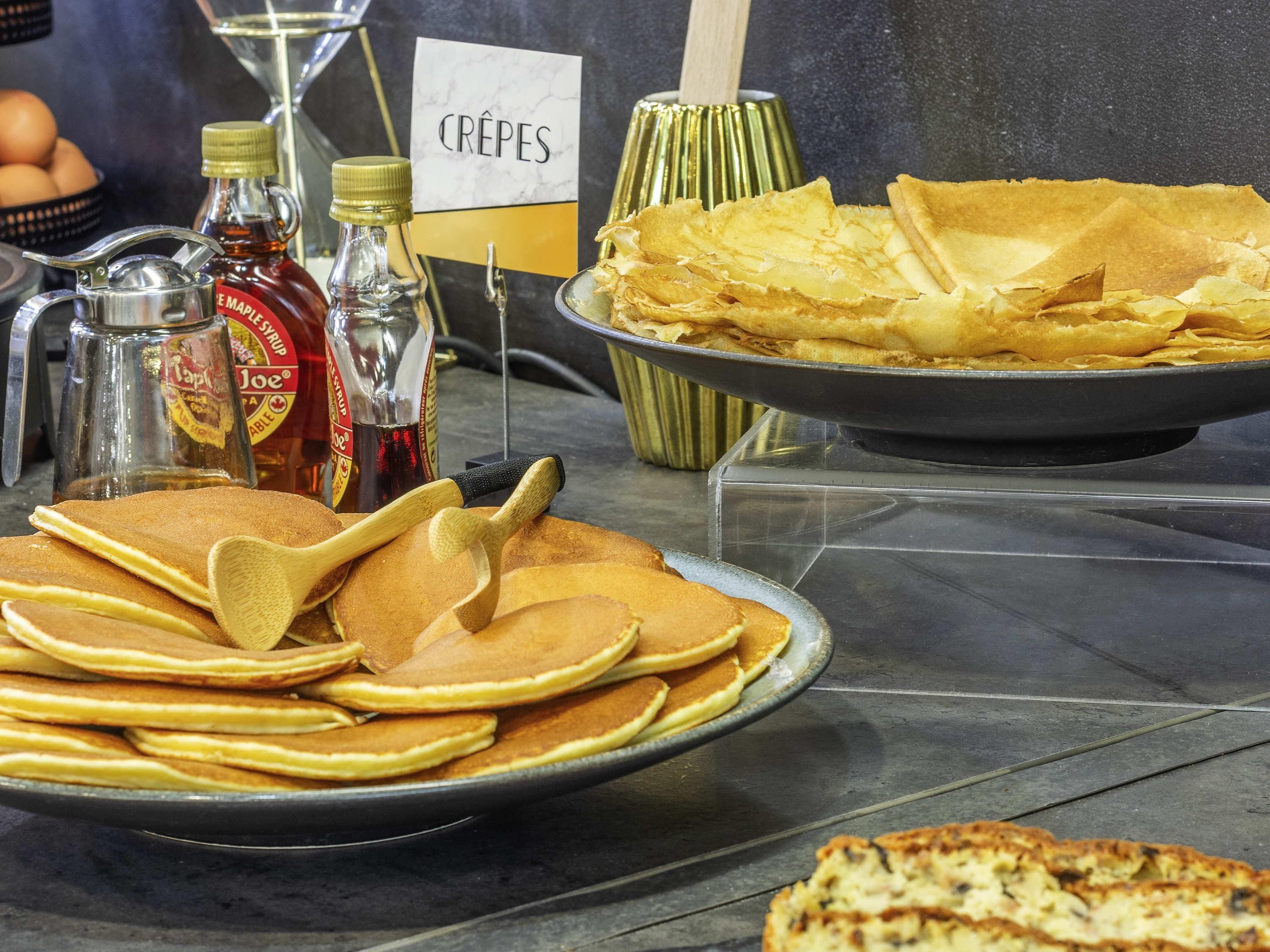 Un buffet de petit-déjeuner avec des crêpes, des galettes, du sirop d’érable et du miel.