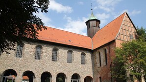 A historic building with a stone facade, arched windows, and a red-tiled roof.
