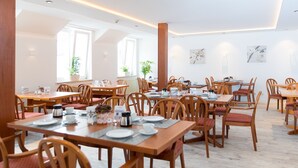 A spacious dining area with multiple wooden tables and chairs, equipped with plates, cups, and a coffee pot.