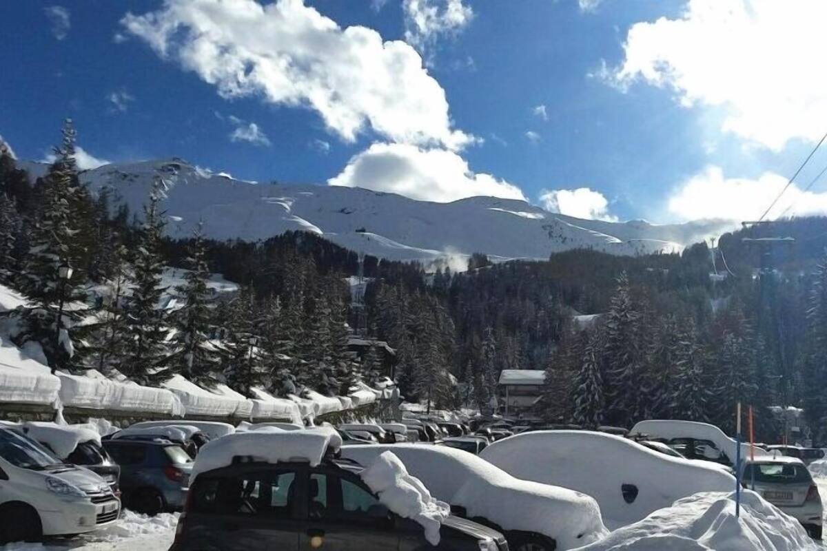 A snowy mountain landscape with parked cars and a clear sky.