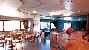 Un restaurante con sillas y mesas de madera, una barra curva y un ventanal grande.