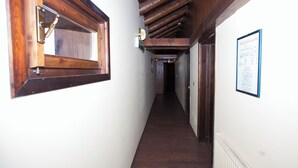 Un pasillo estrecho con vigas de madera, una ventana y un letrero en la pared.