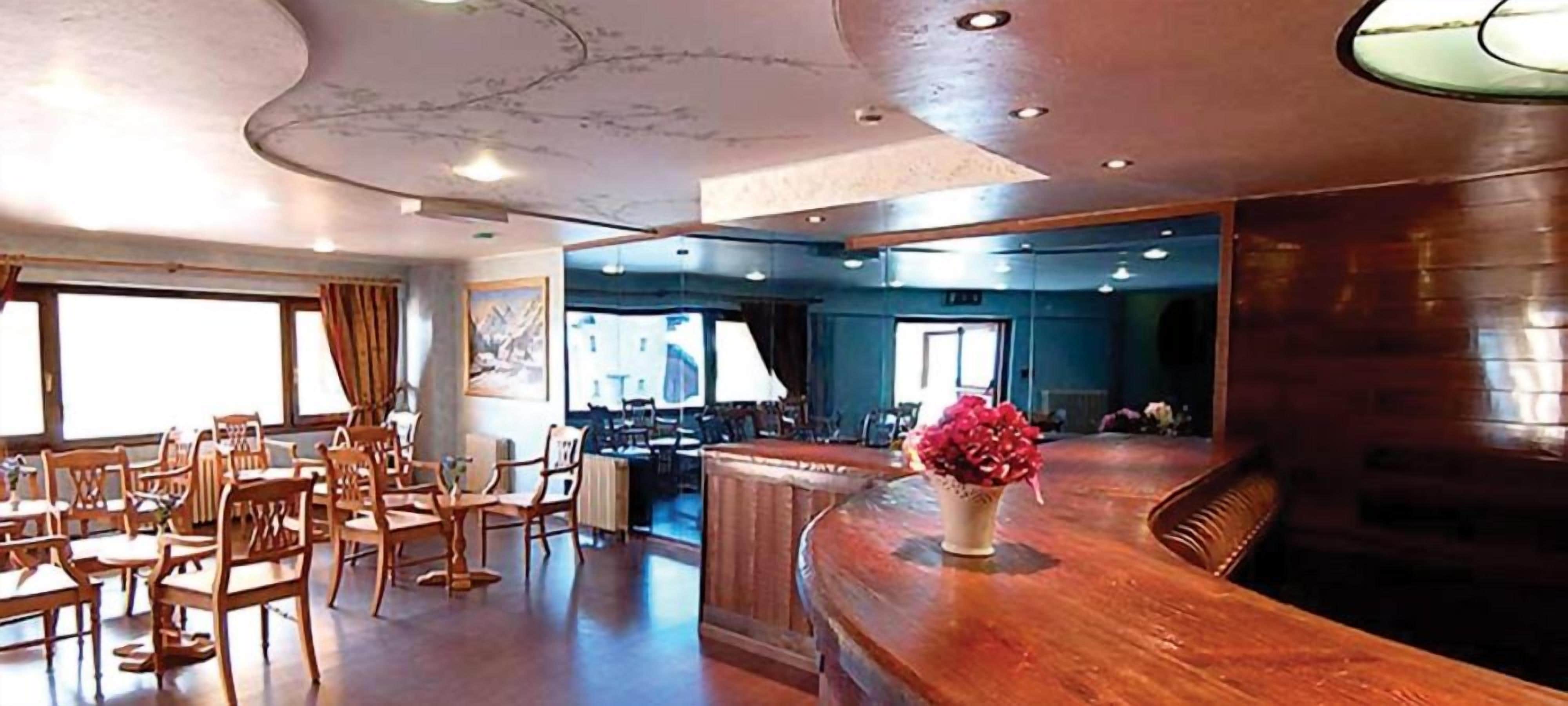Ein Restaurant mit Holztischen und -stühlen, einer gebogenen Bar und einem großen Fenster.