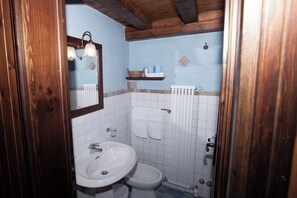 A bathroom with a wooden ceiling, a white sink, a toilet, and a towel rack. - Club Esse Pila 2000 (Gressan)