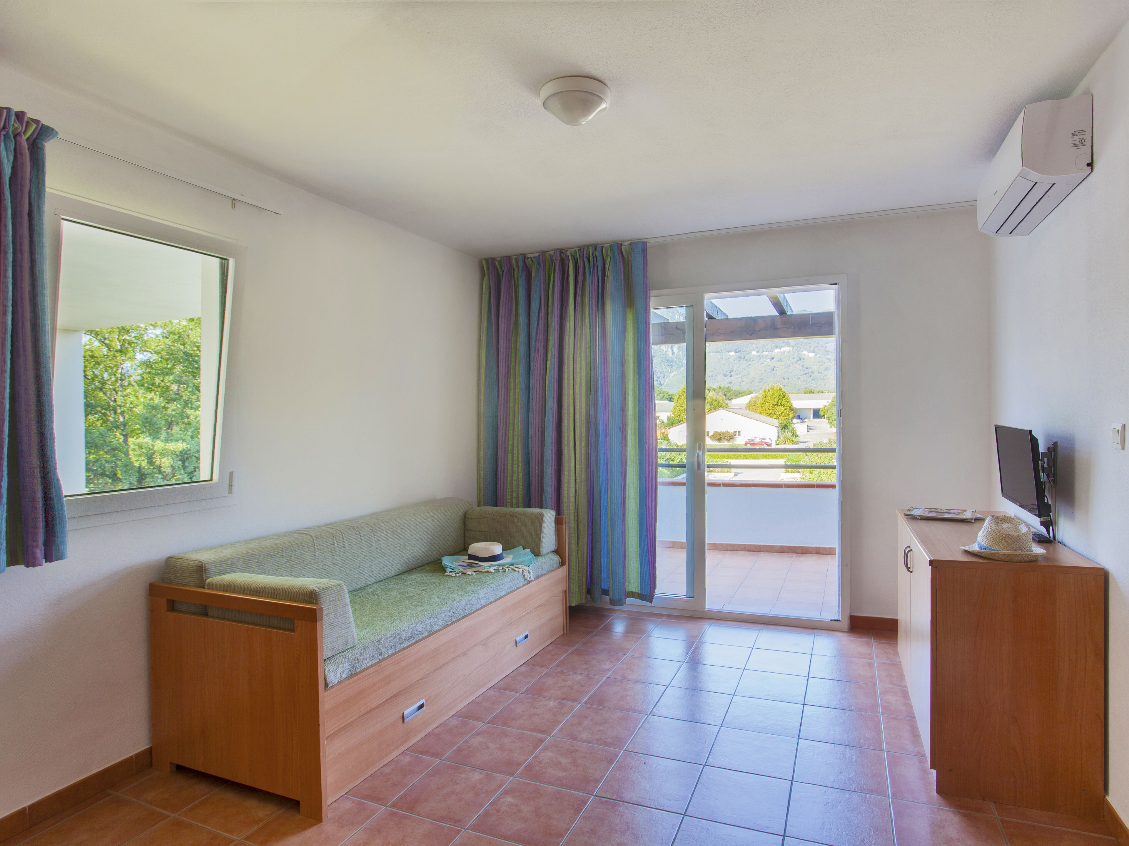 A room with a sofa, a television, and a sliding glass door leading to an outdoor area.
