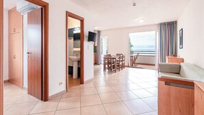 A spacious living area with a dining table, a sofa, and a view of the sea. - Vacanceole Sognu Di Rena (San-Nicolao)