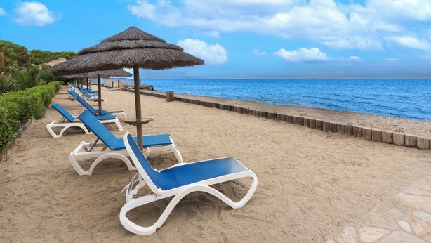 A beach with rows of sun loungers and thatched umbrellas, a wooden walkway, and a view of the sea. - Vacanceole Sognu Di Rena (San-Nicolao)