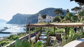 A coastal view with a white building, a wooden pergola, and cacti.