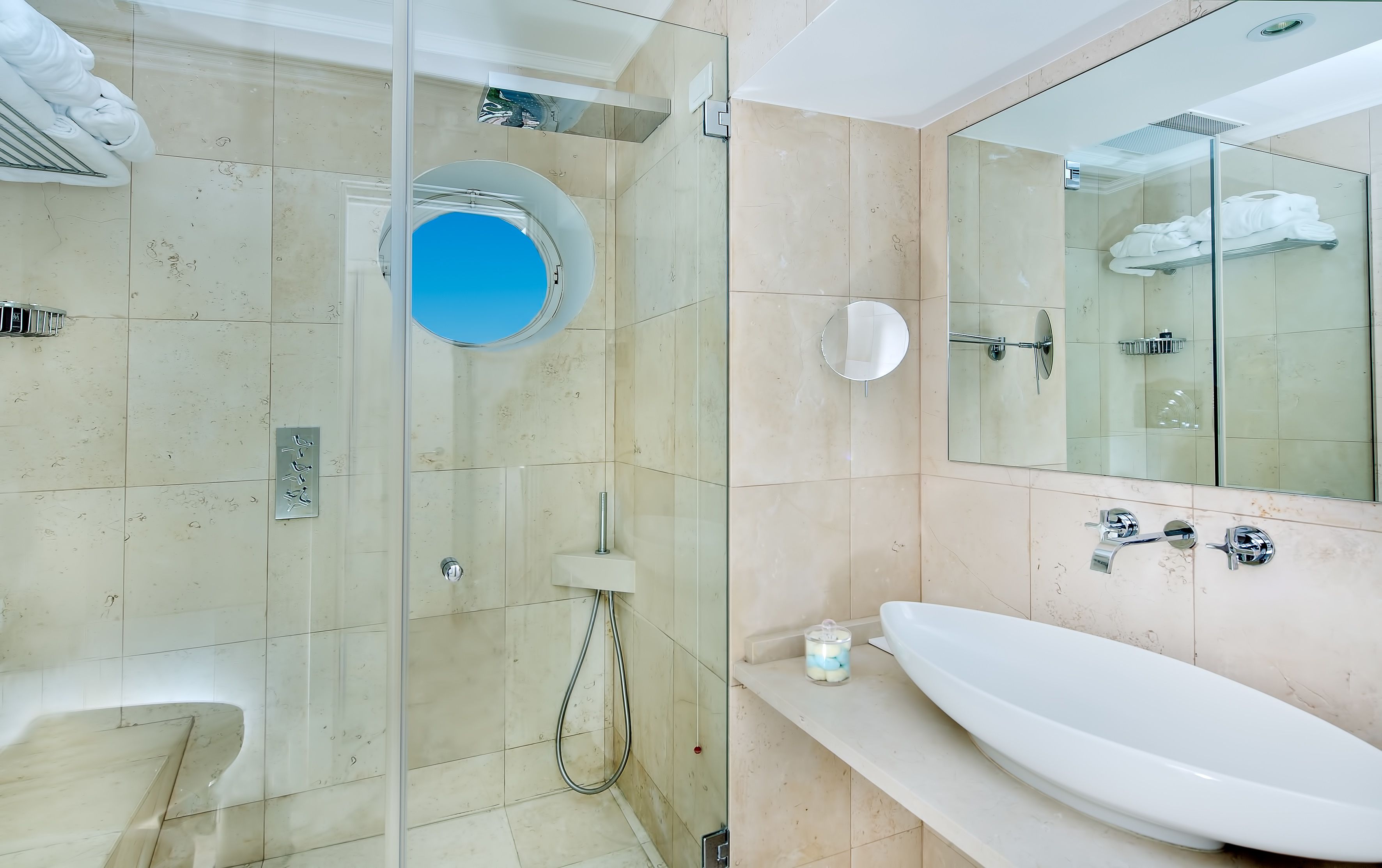 Une salle de bain moderne avec une douche à parois de verre, un grand miroir et un lavabo blanc.