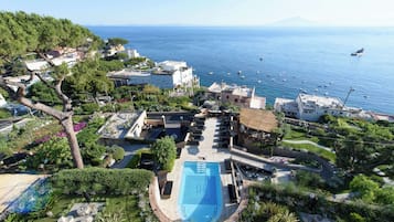 Relax by the resort's central pool surrounded by lush gardens and seating areas, with breathtaking views of the calm sea.