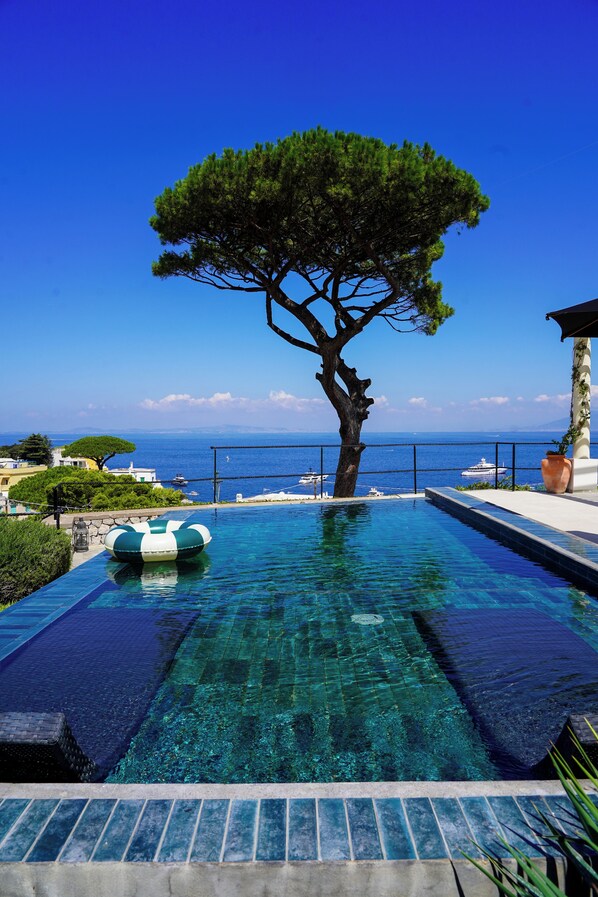 A clear blue swimming pool with a tree in the center, a view of the sea, and a lifeguard stand. - Villa Marina Capri - Preferred Hotels & Resorts (Capri)