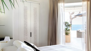 A modern bedroom with a large bed, a ceiling light fixture, a view of the outdoors, and a potted plant. - Villa Marina Capri - Preferred Hotels & Resorts (Capri)