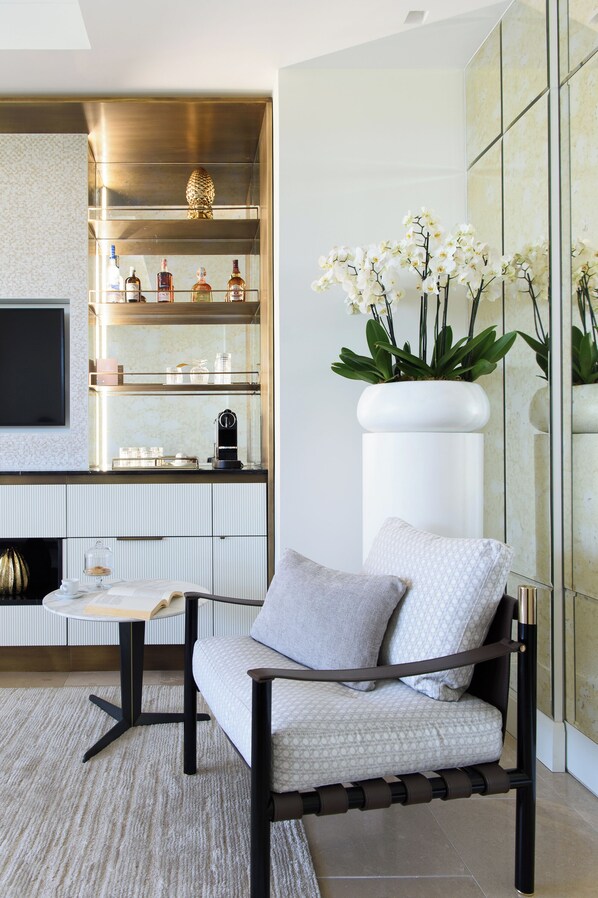 A modern living room with a sofa, a coffee table, and a TV. There is a bookshelf with decorative items and a potted plant. - Villa Marina Capri - Preferred Hotels & Resorts (Capri)