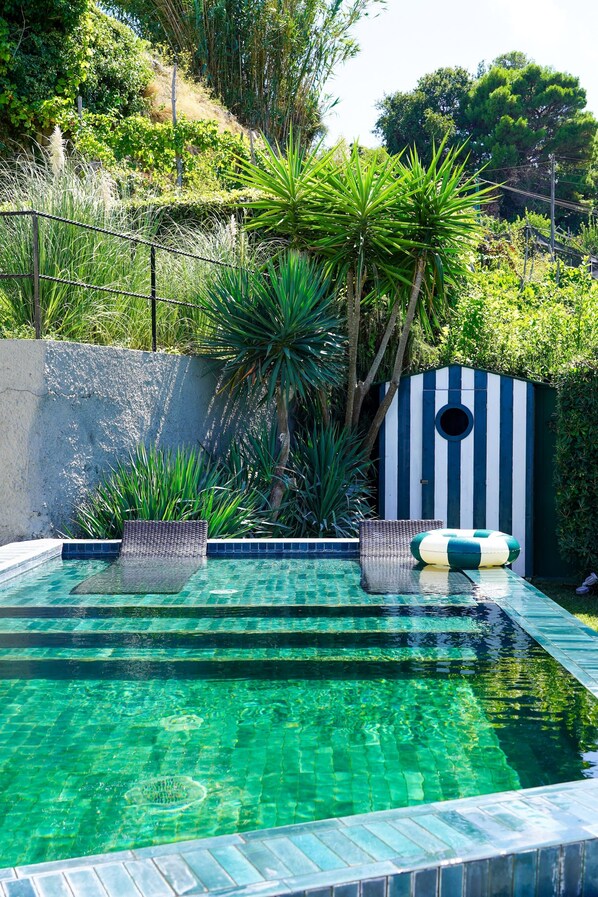 A swimming pool with clear water, surrounded by lush greenery and a striped structure. - Villa Marina Capri - Preferred Hotels & Resorts (Capri)