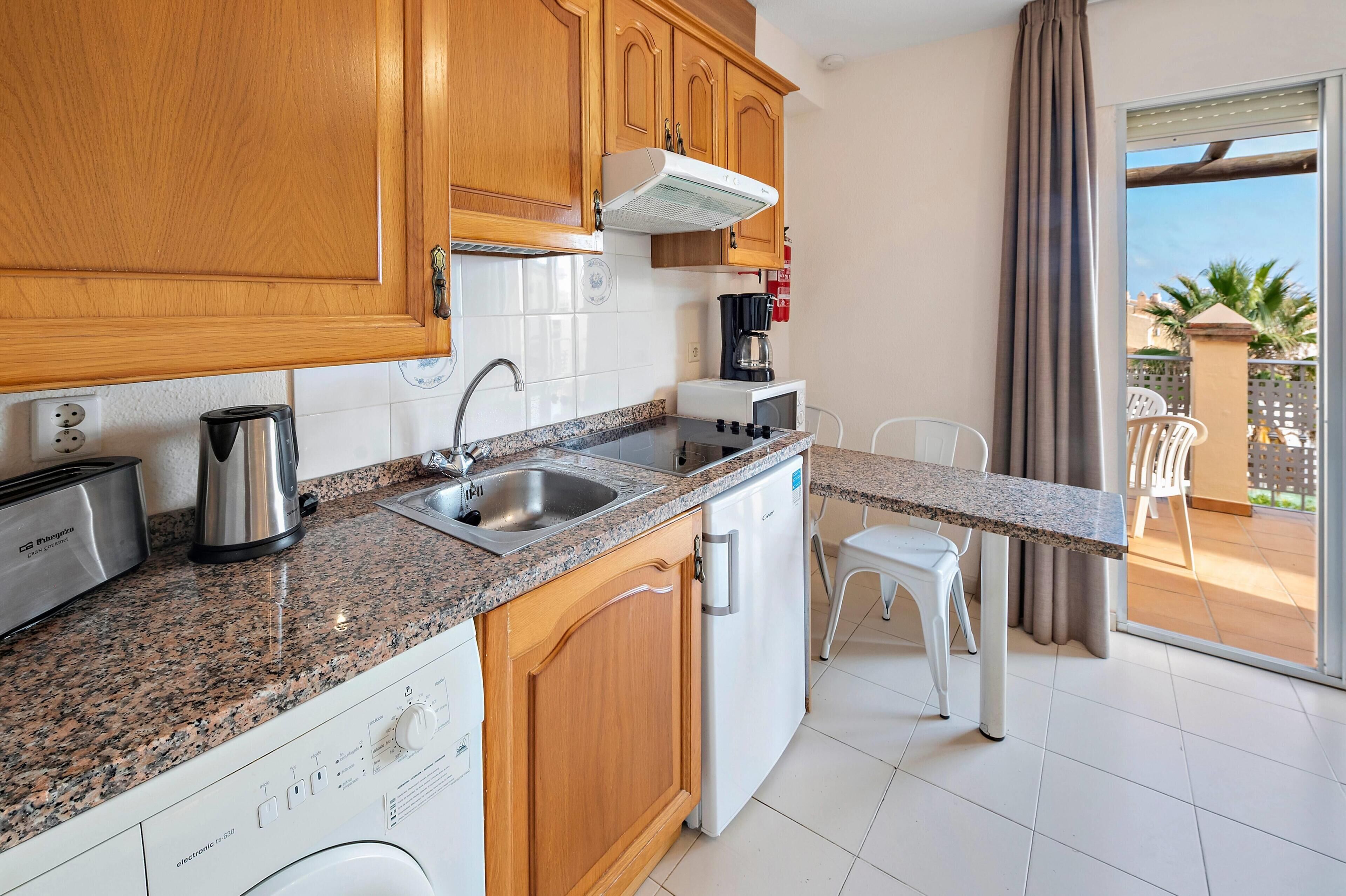 A kitchen with wooden cabinets, a granite countertop, a coffee maker, a toaster, and a dishwasher.